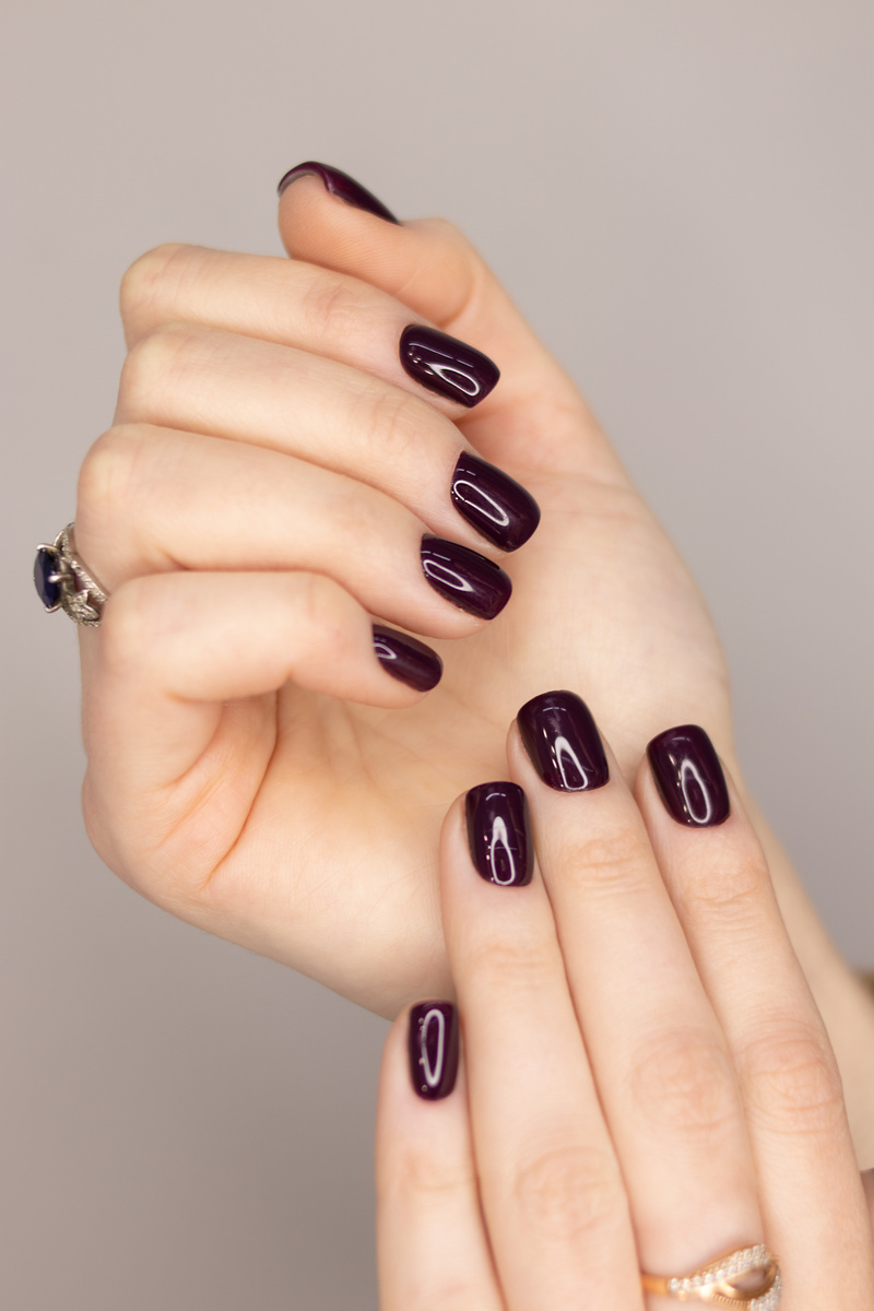 Dark gel polish on the nails of a girl. Dark manicure with soft square nails. Gel polish coatings
