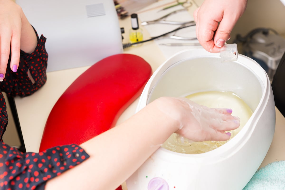 Woman Dipping Hand in Parrafin Wax Spa Treatment